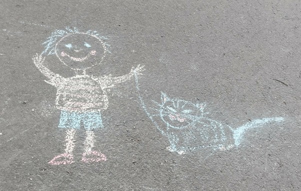 Kinderzeichnung mit Kreide auf dem Asphalt, ein fröhliches Kind mit Katze an der Leine 
